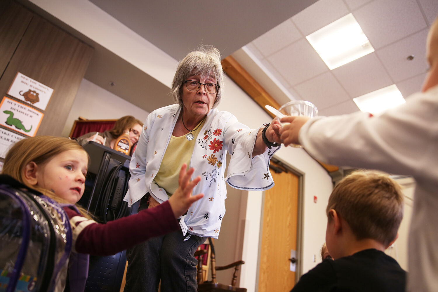 Mary Rhoads hands out ice cream cups after adding the selected toppings